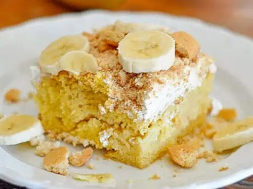 banana pudding poke cake on a white plate on a table.