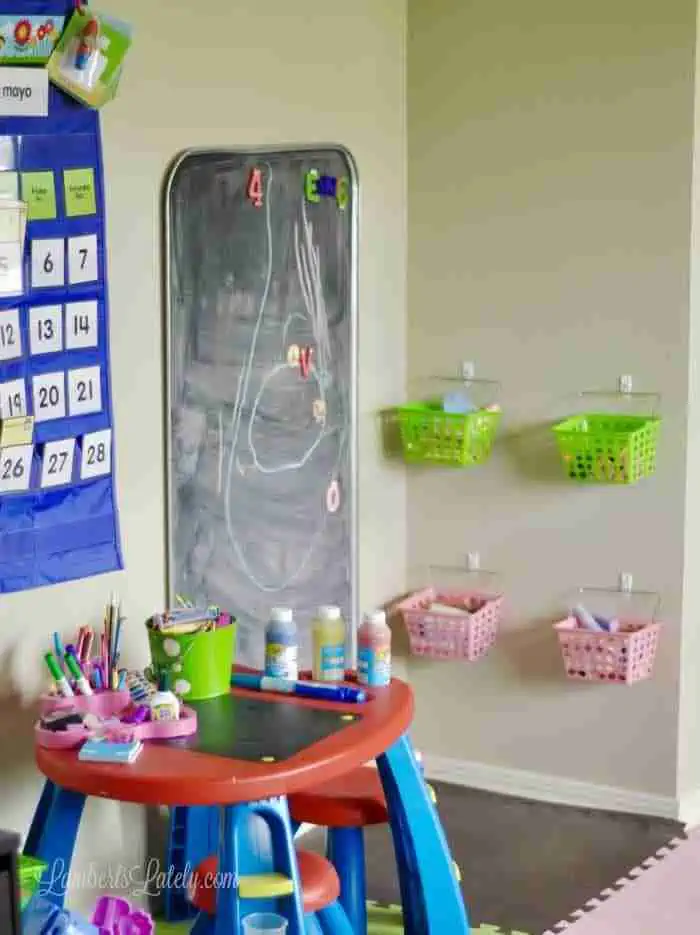 blue pocket calendar, chalkboard, baskets with chalk, art table in a playroom.