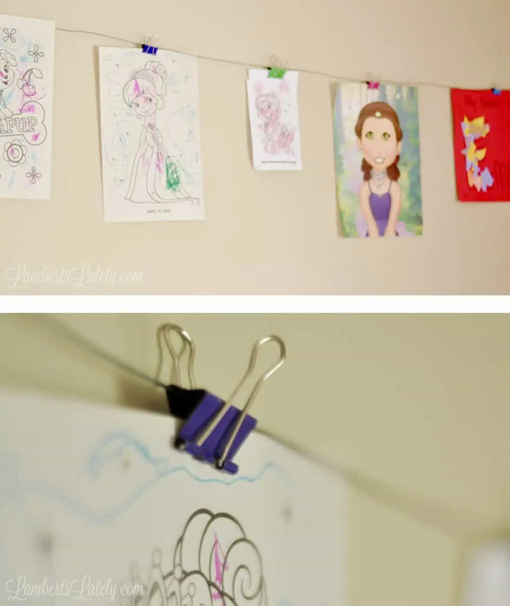 metal wire and binder clips holding artwork on a wall.
