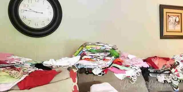 clothes on hangers, piled on couch.
