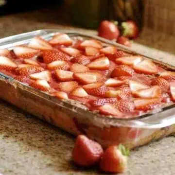 chocolate strawberry earthquake cake in a glass baking dish, surrounded by fresh strawberries.