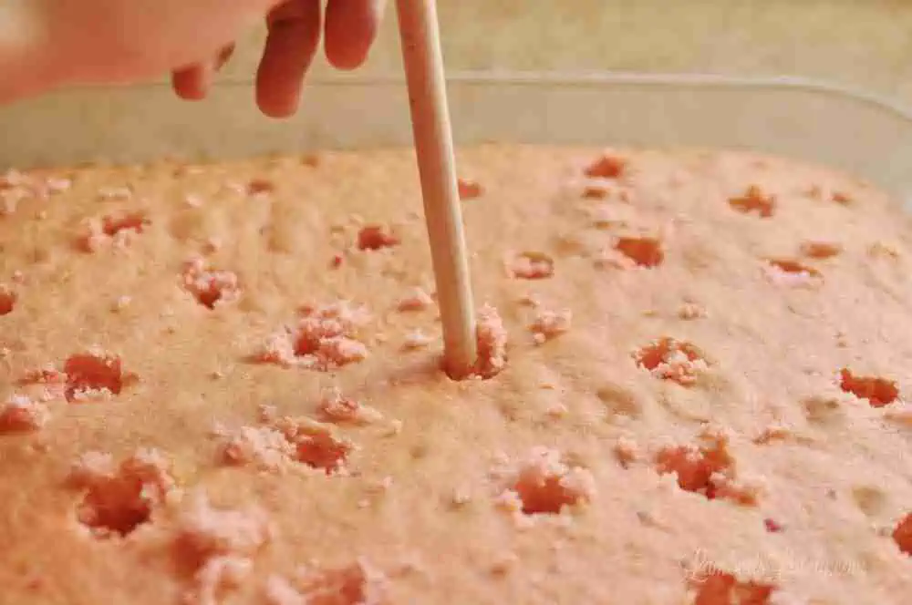 punching holes in a cake with the back of a wooden spoon.