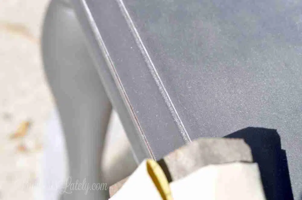 sanding the edge of a gray painted end table.