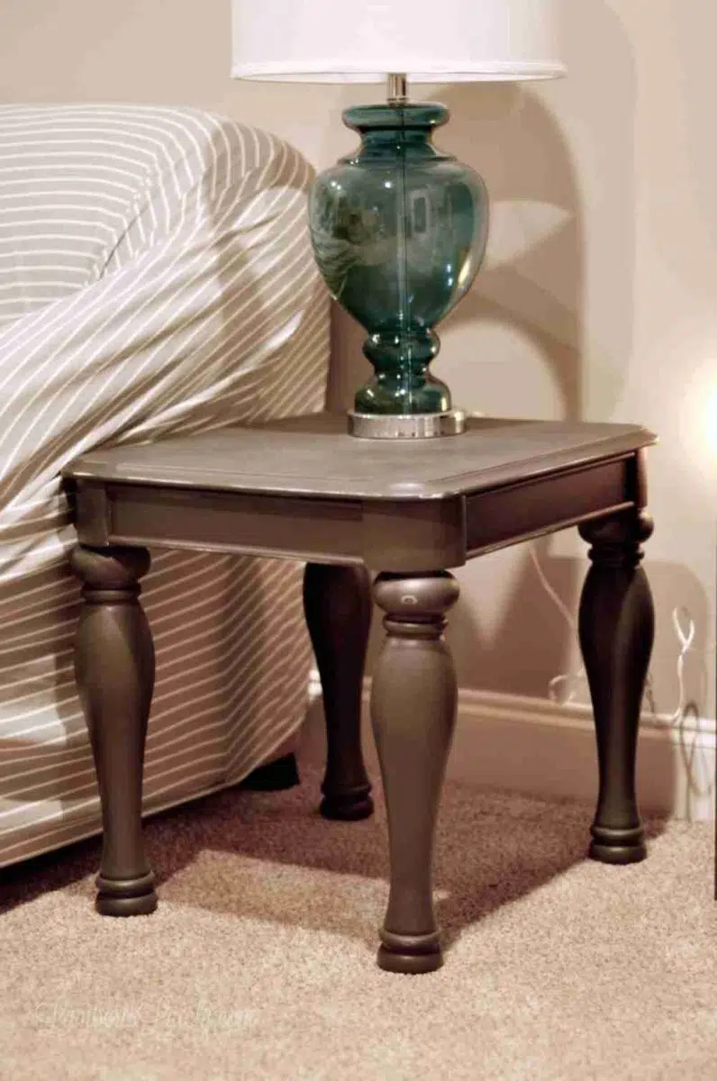 dark gray side table with lamp on top, next to a couch.