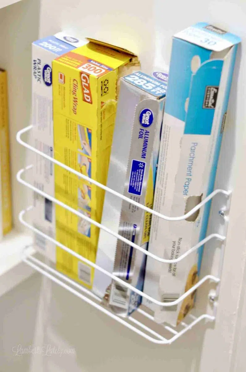 rack holding aluminum foil and plastic wrap on a wall.