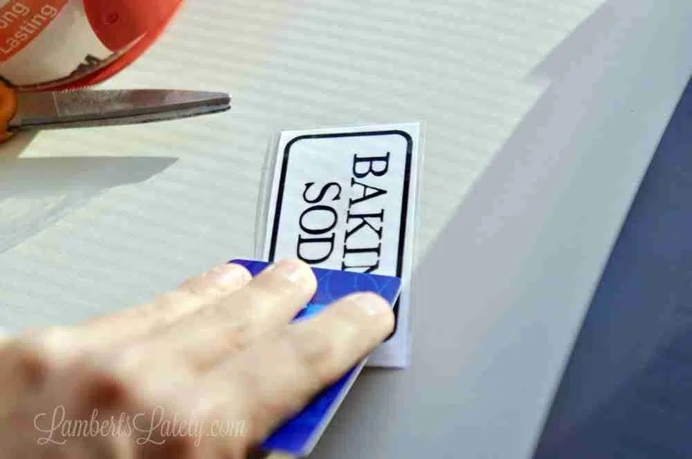dragging credit card over baking soda label with tape on top.