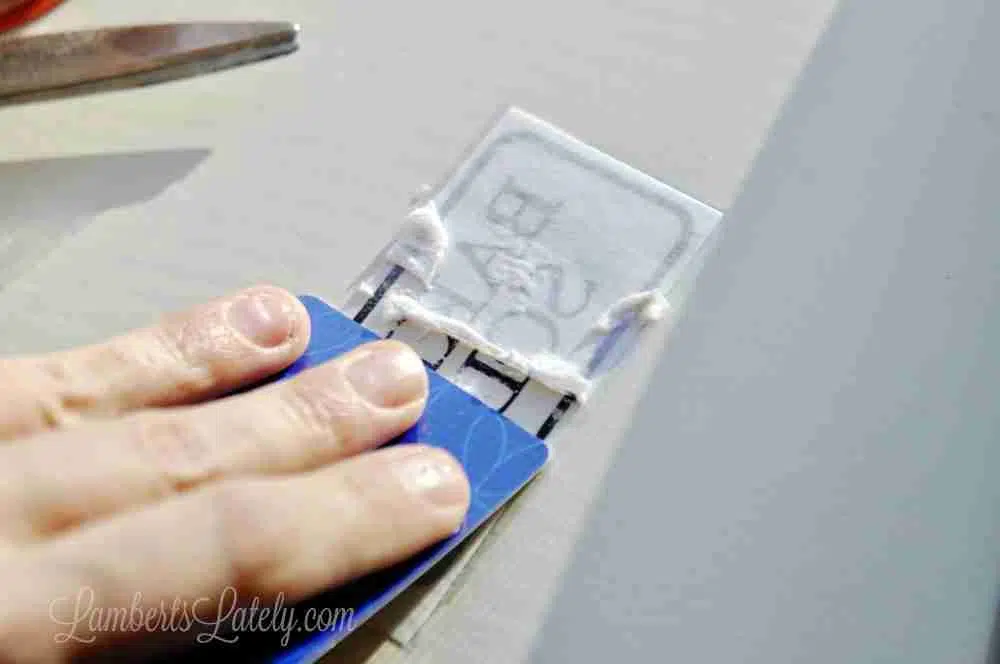 scraping a credit card on back of tape to release white paper.