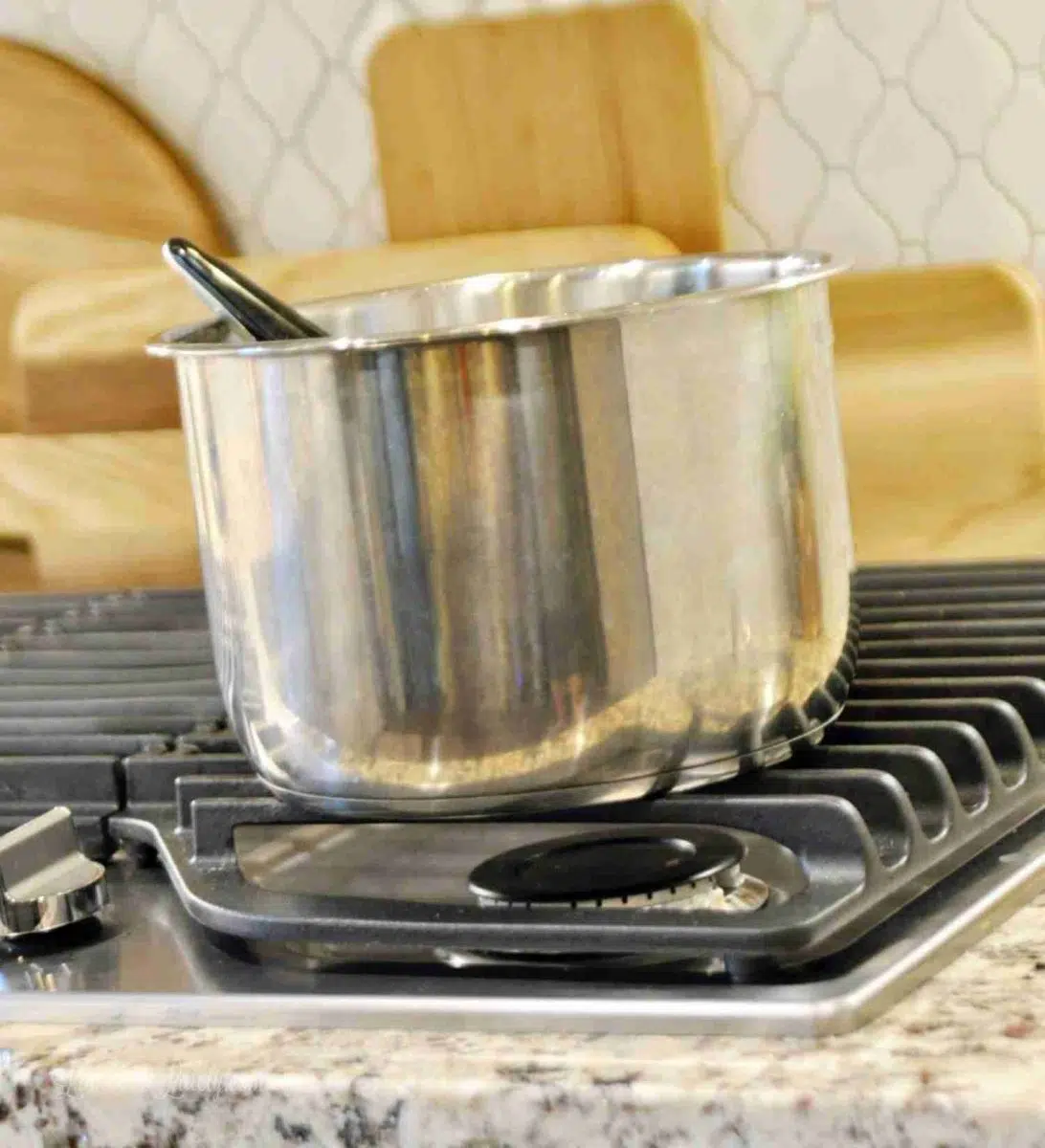 Inner pot from Instant Pot cooling on a stove grate.