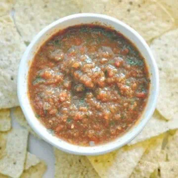 bowl of salsa surrounded by chips.