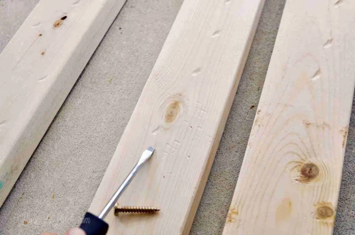 distressing 2x4 wood with a screwdriver and screw.