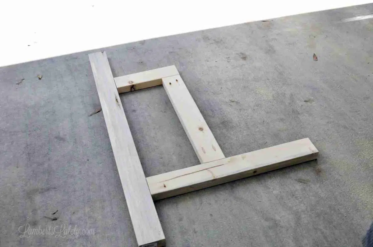 wood lying on a garage floor with straight piece of 2x4 to level.