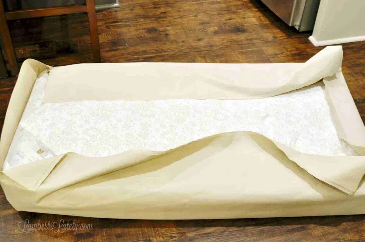 draping crib mattress in exterior fabric.