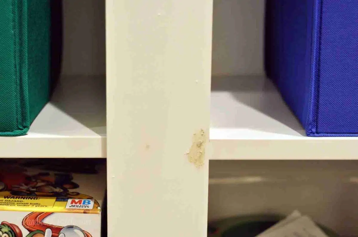 wood putty over a hole in white shelf.