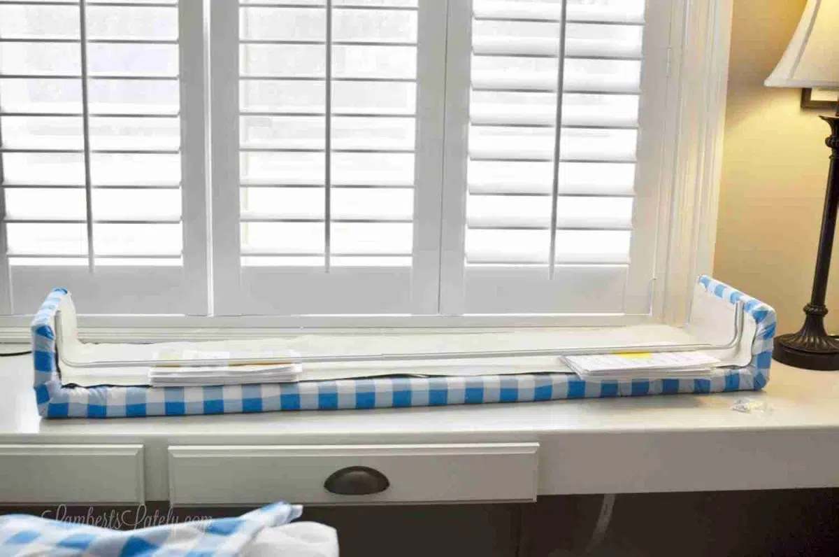 cornice board with curtain rod in inside on the back, held up by stacks of papers.