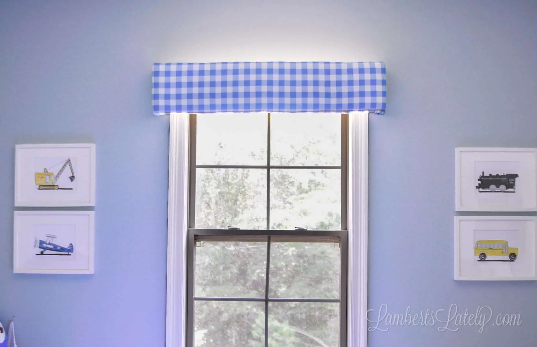 cornice board hung above a window, with framed pictures on each side of window.