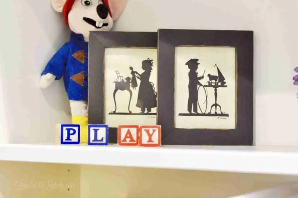 letter blocks, art, stuffed animal on a white shelf.