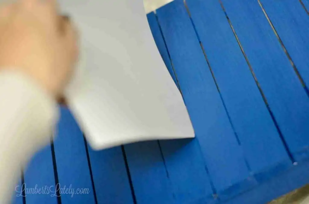 putting piece of cardstock between slats of a table.
