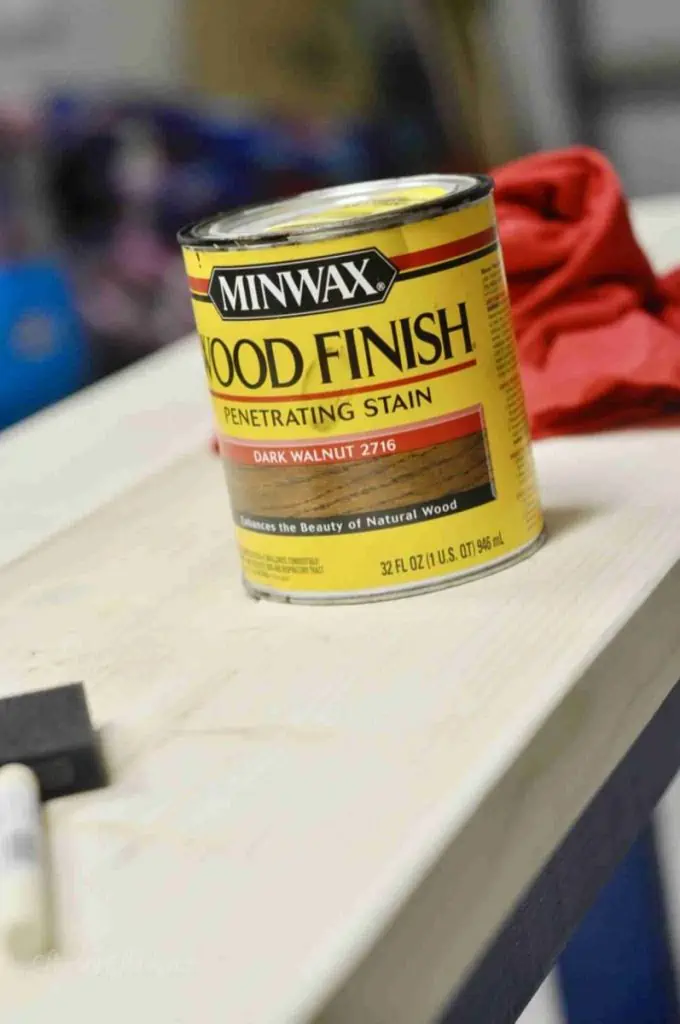 can of stain and brush on a wood table before staining.