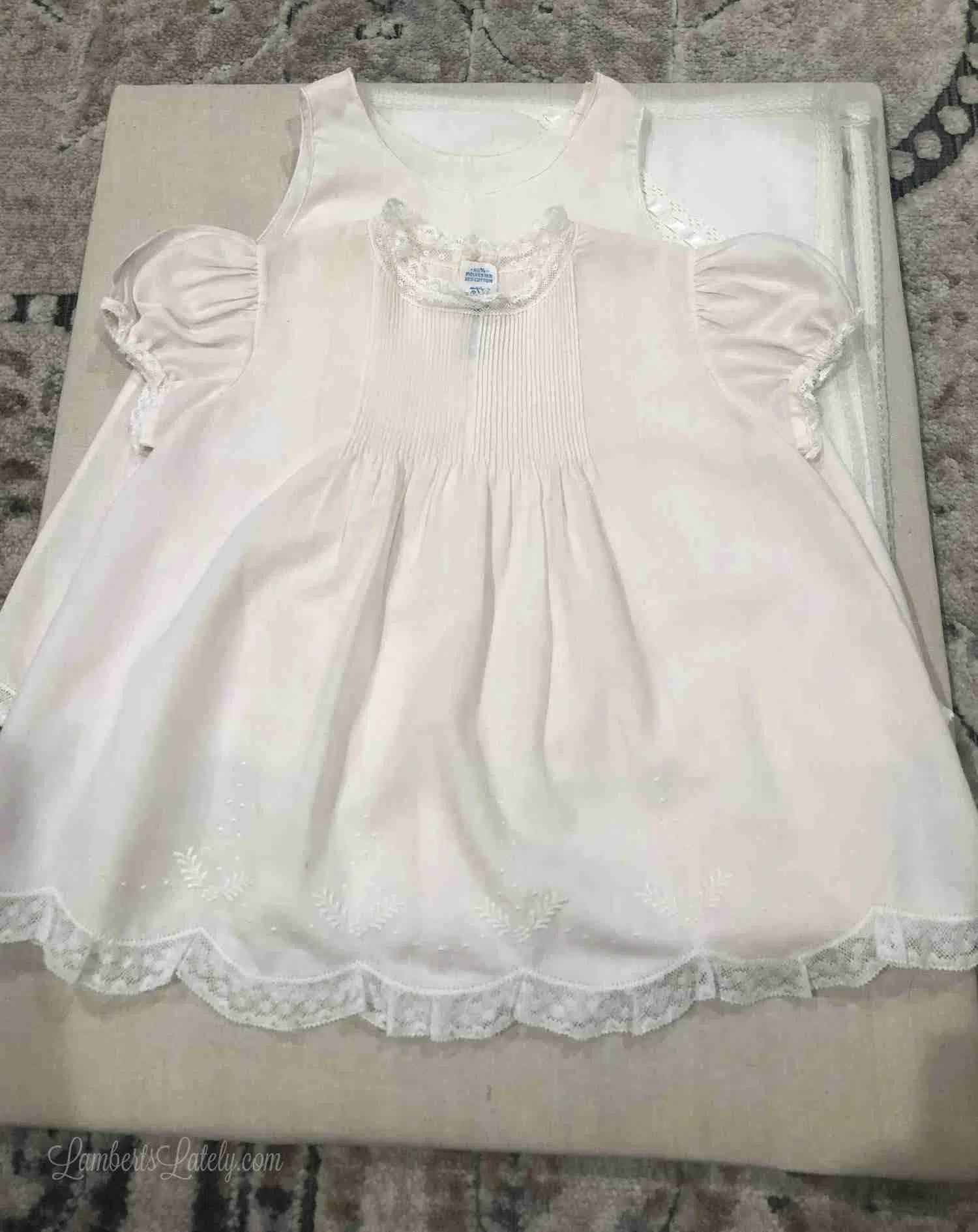 baby dress laid on a piece of brown cloth to be framed.
