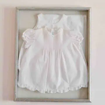 pink baby dress in a shadow box on a wall.