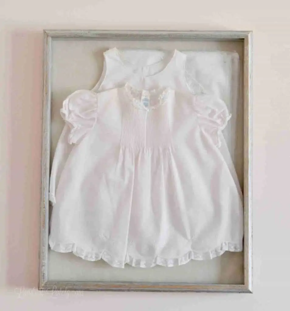 pink baby dress in a shadow box on a wall.