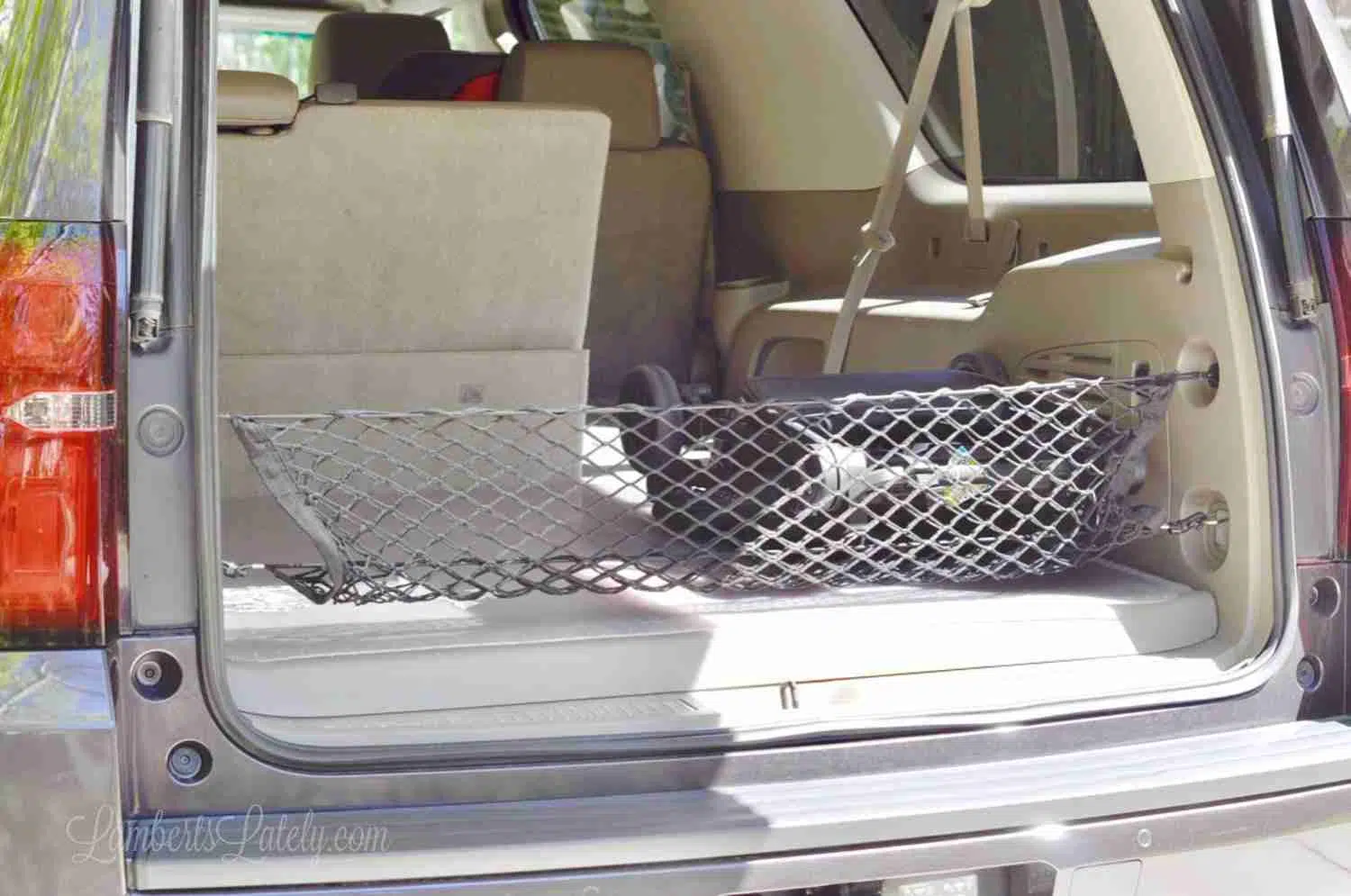 back of a suburban open with one seat folded down and a black net.
