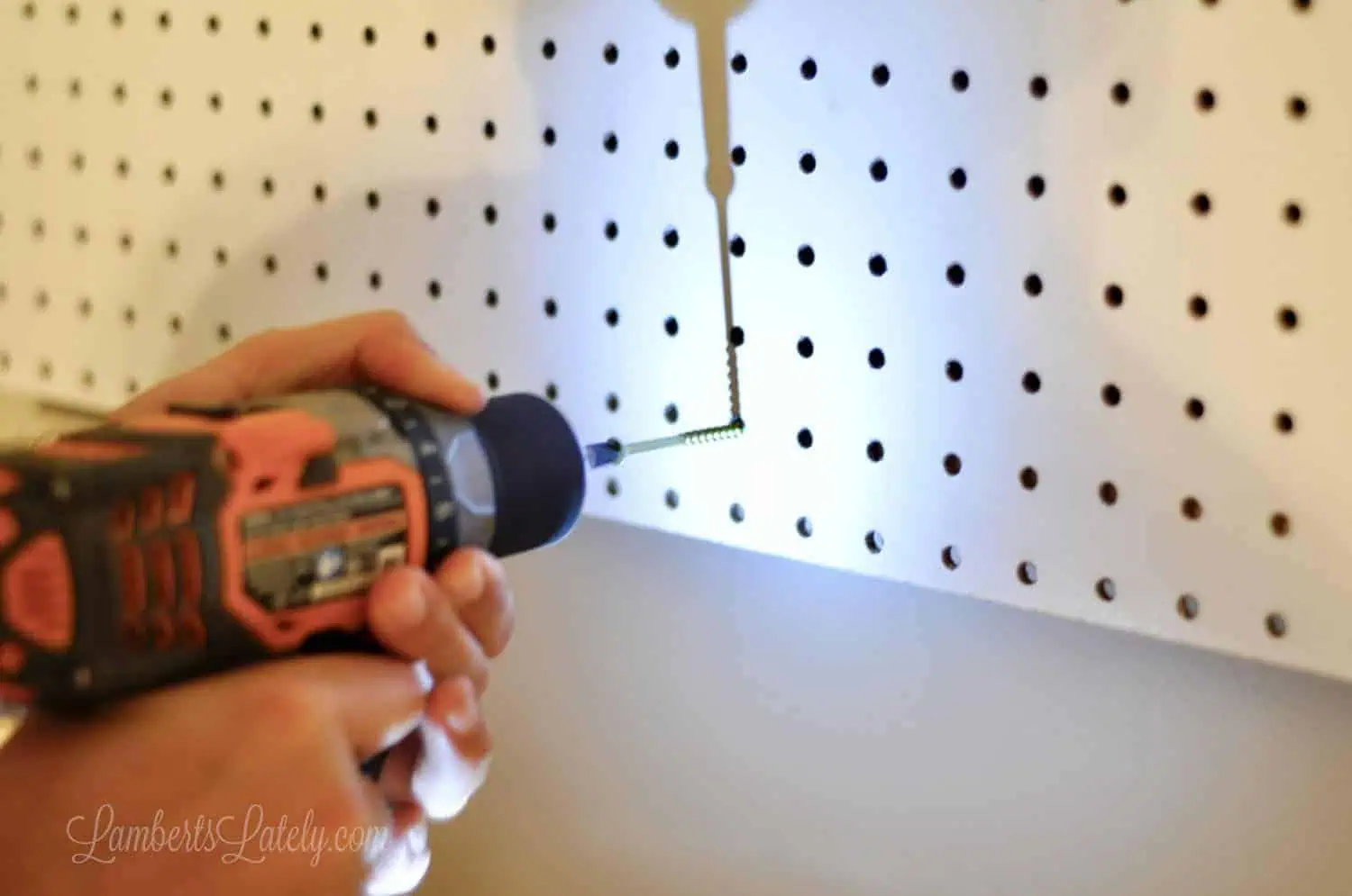 screwing peg board into wall.