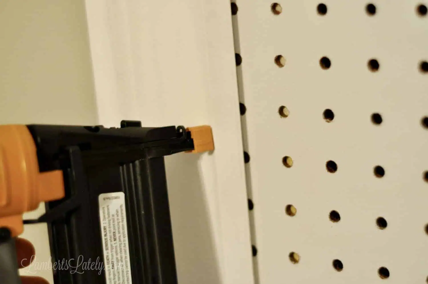 nailing crown molding into pegboard edge with a pneumatic nail gun.