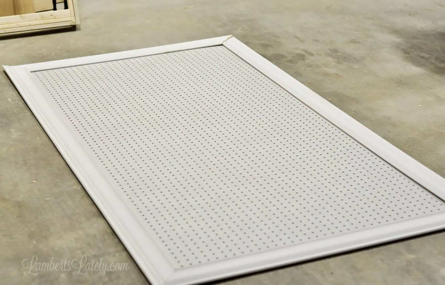 pegboard surrounded by cut crown molding on a garage floor.