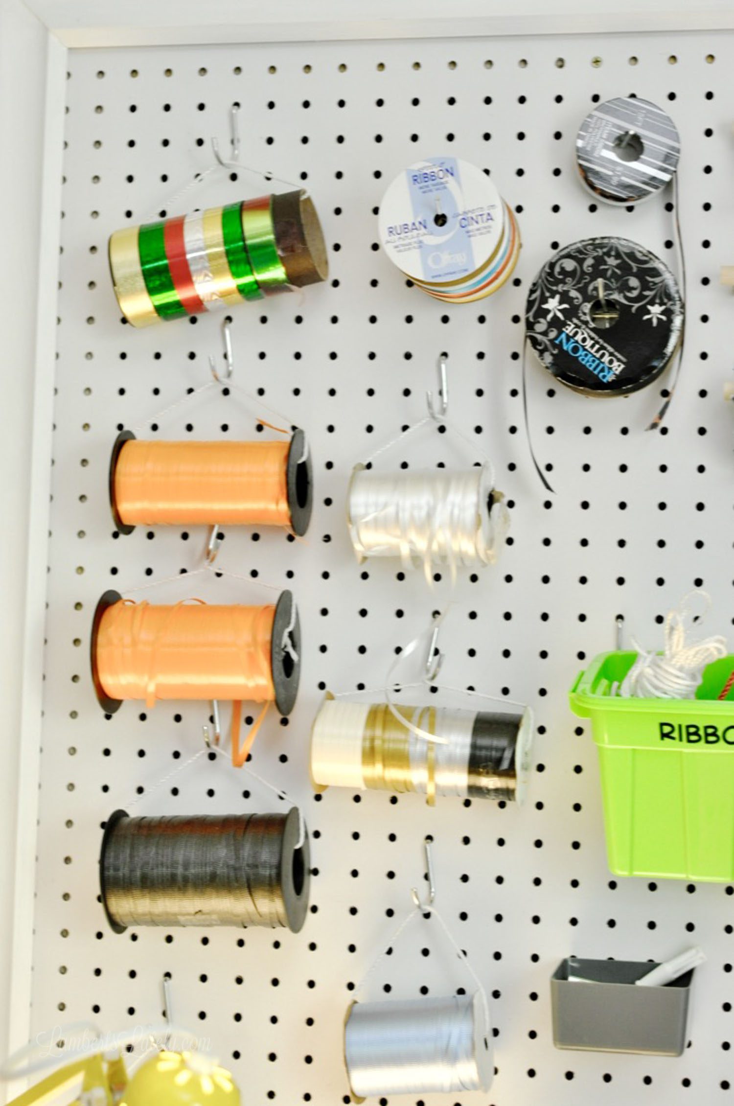 spools of ribbon hanging on a craft room peg board