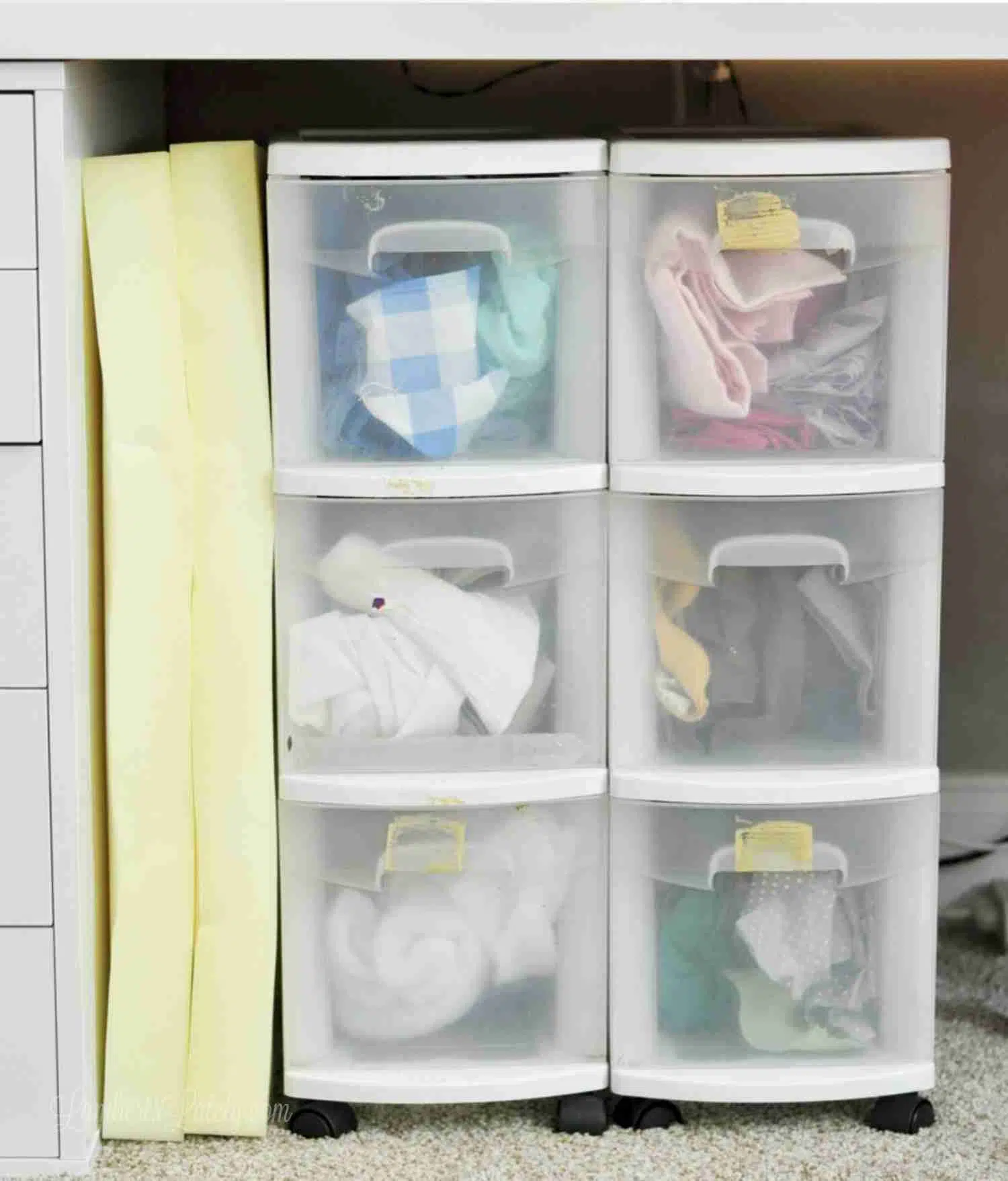 plastic rolling shelves holding fabric under a desk