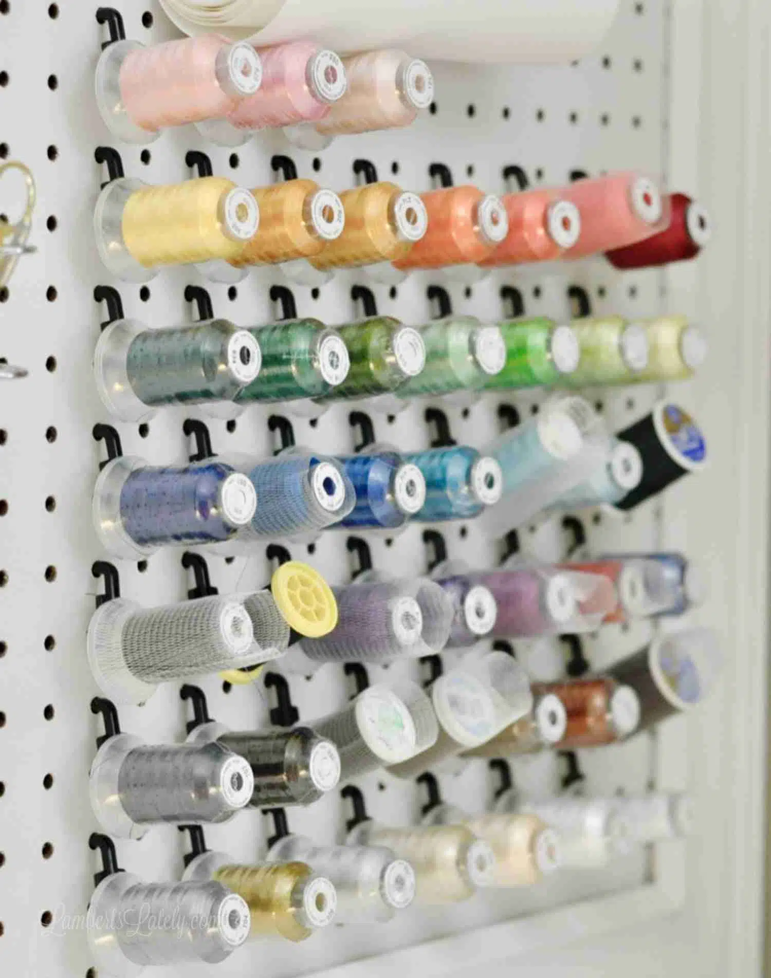 different colors of thread organized on a peg board in a craft room