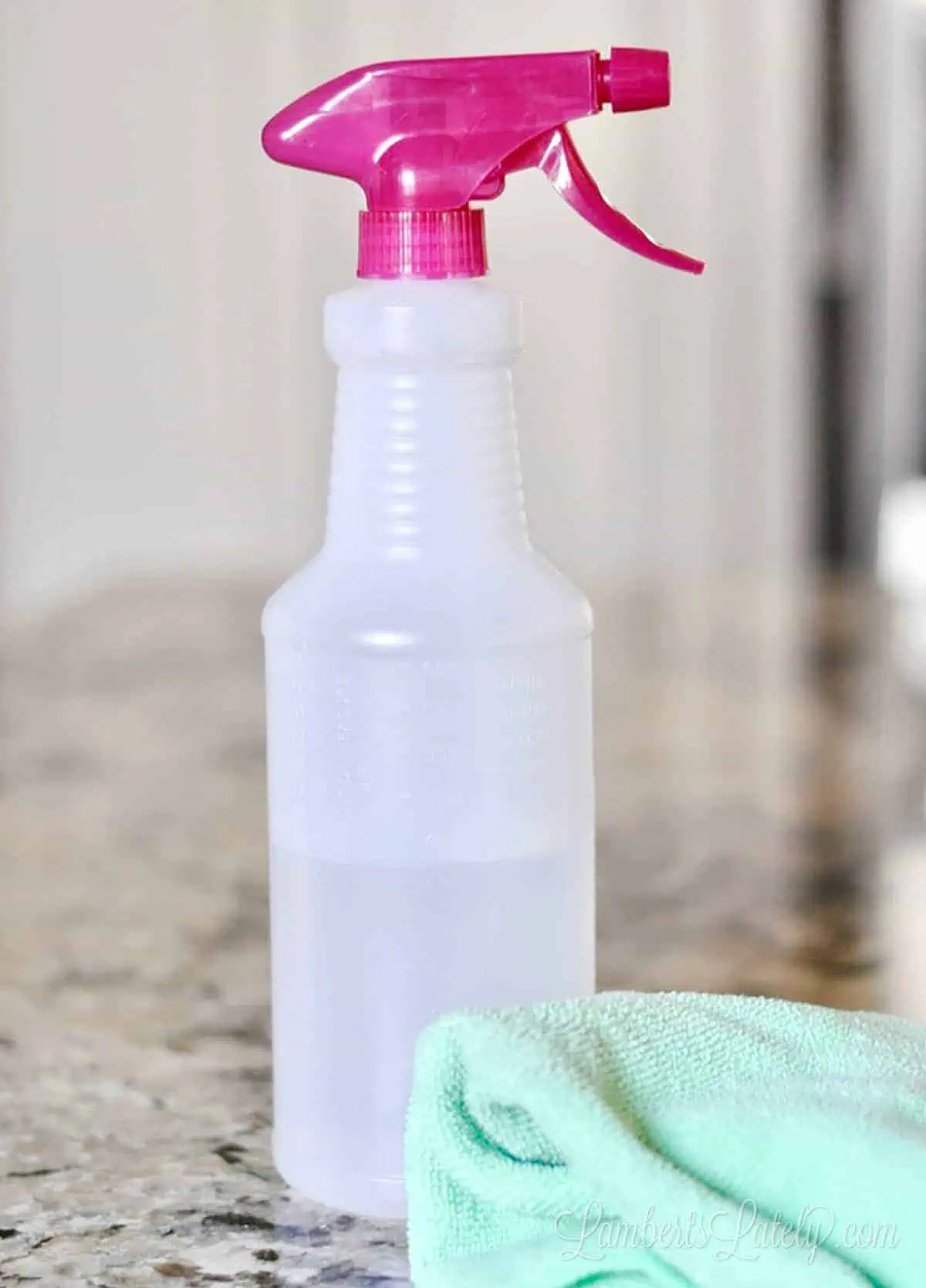 bottle of cleaner and a microfiber cloth on a granite countertop.