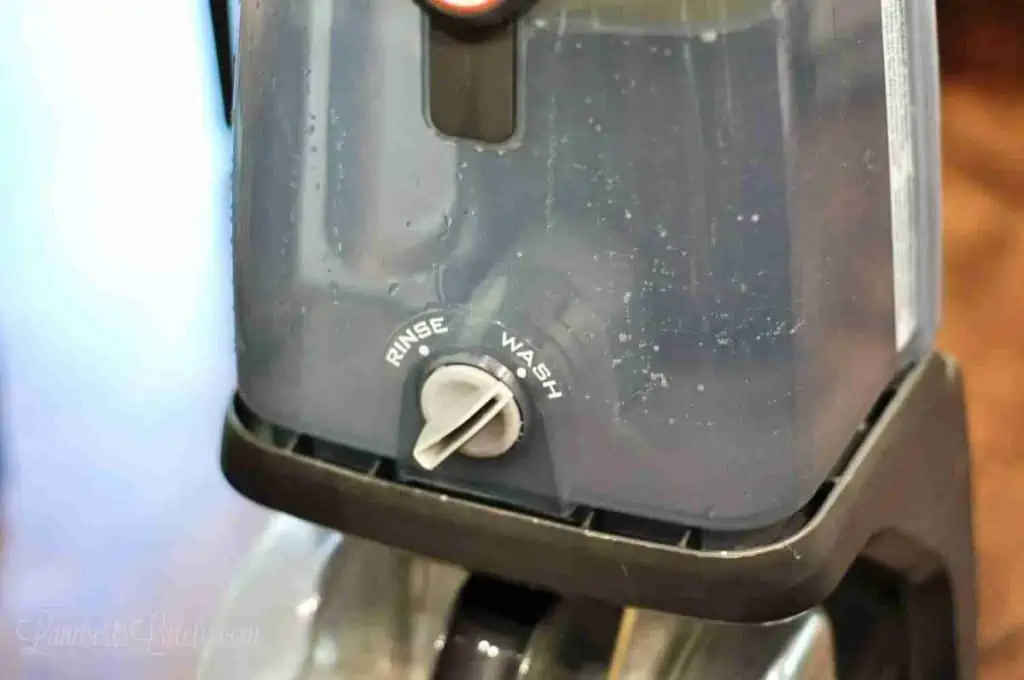 water tank of a carpet cleaner pointing to the wash cycle.