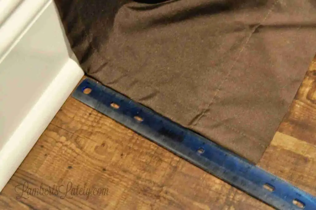 measuring curtains on a floor with a ruler; lots of excess fabric on the floor.