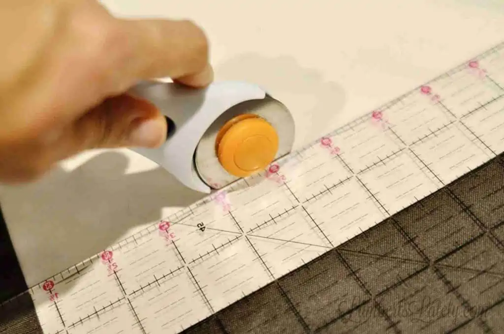 cutting curtain fabric with a rotary cutter, using a quilting ruler.
