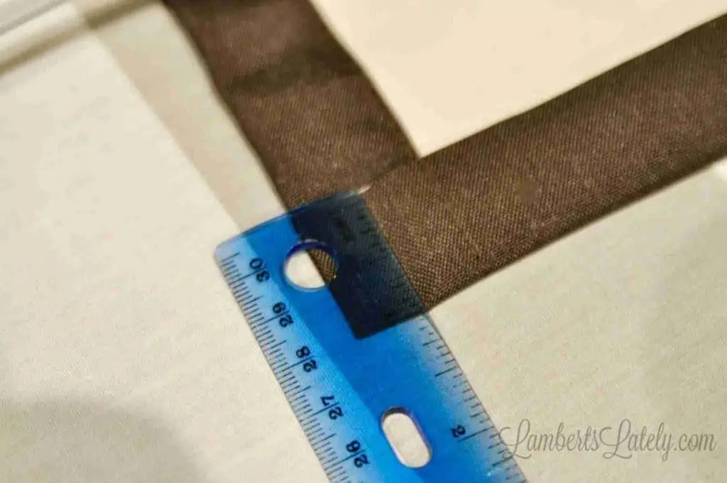 measuring a 1" hem of curtain with a ruler.