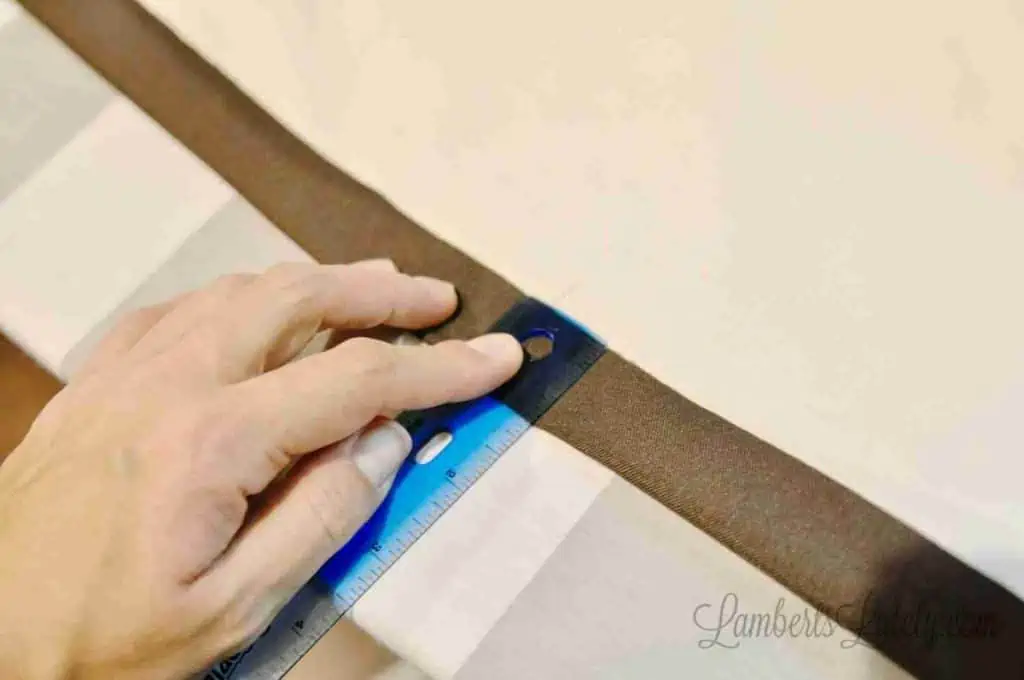 measuring a 1" hem of curtain with a ruler.
