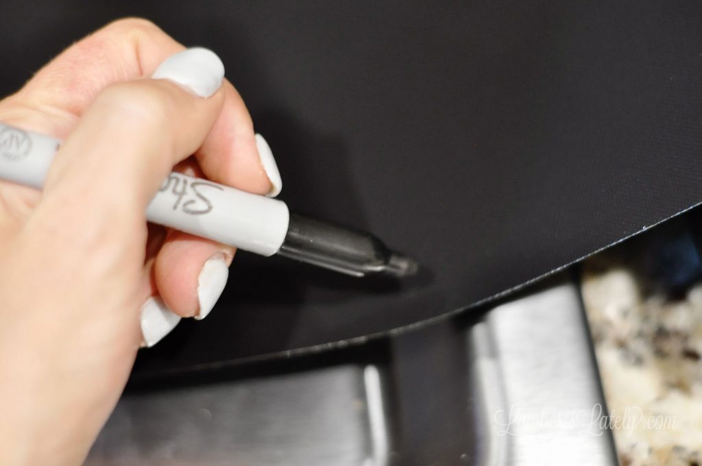 tracing the shape of a stove on the splatter guard with a sharpie