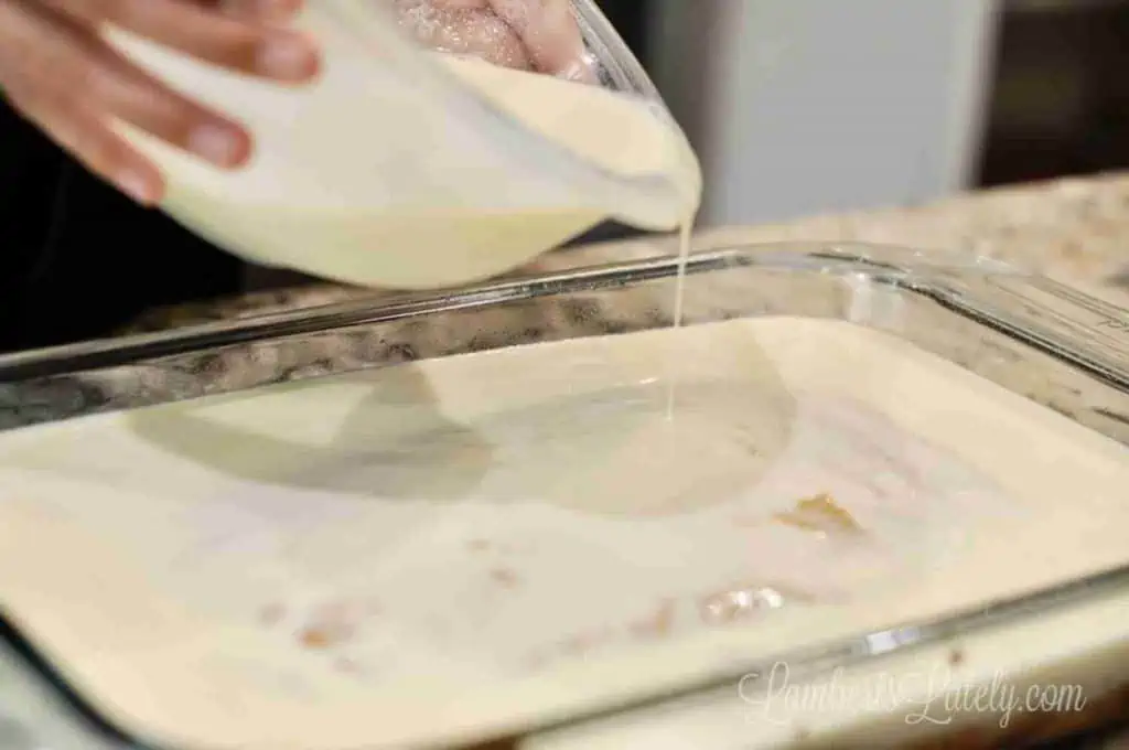 pouring tres leches mixture over a pumpkin spice cake.