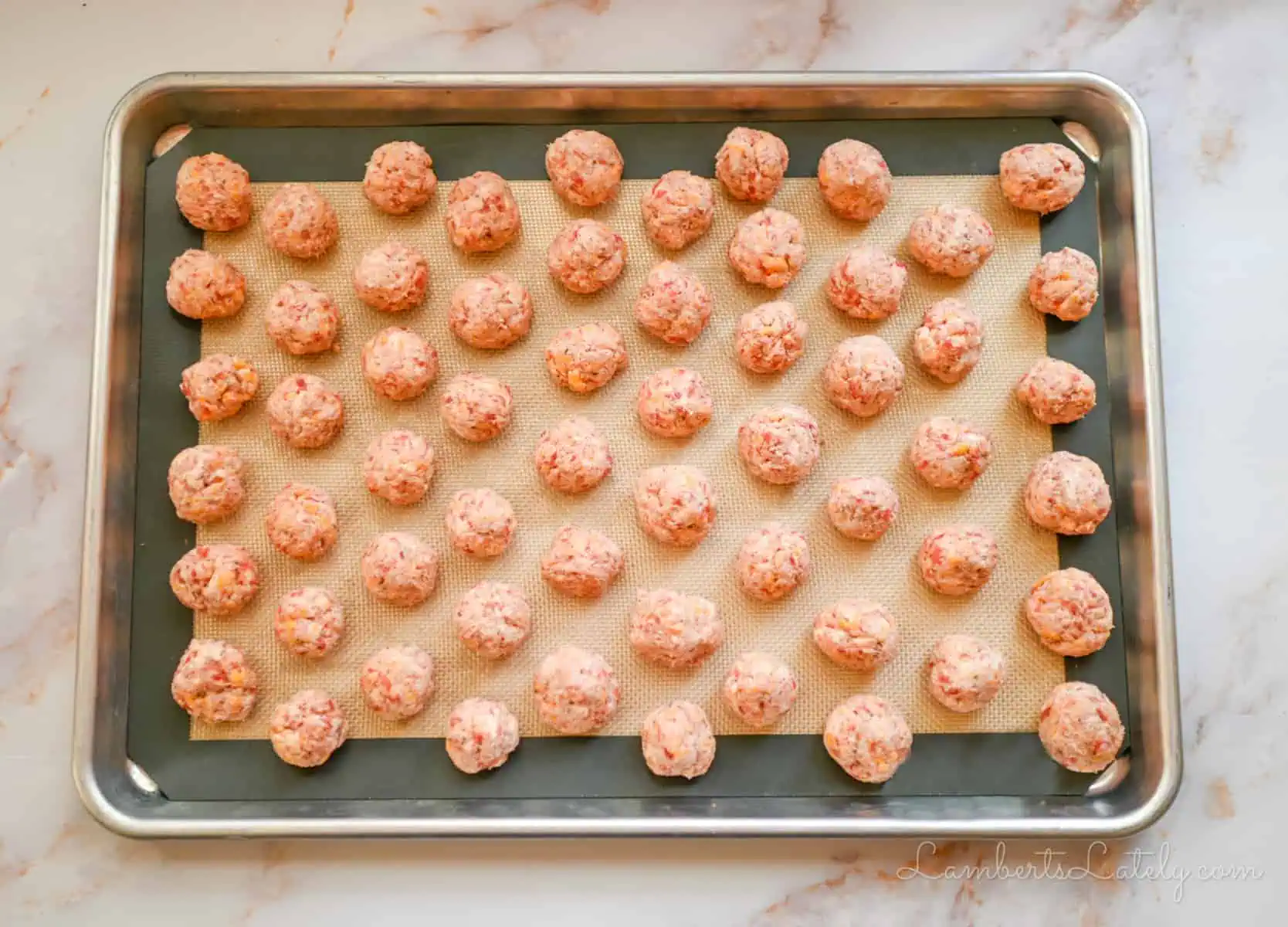 rolled sausage balls on a cookie sheet.