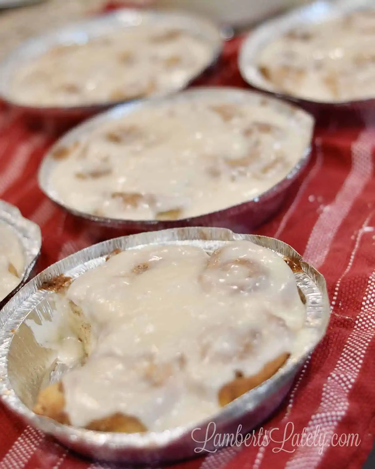 cream cheese cinnamon rolls cooling on a red towel.