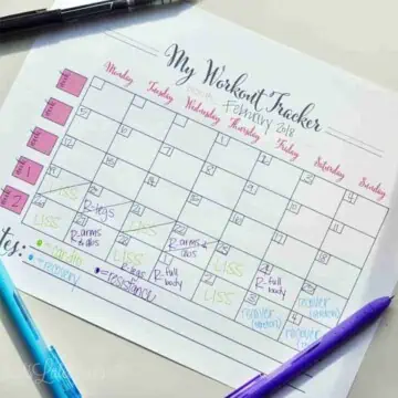 free printable workout calendar on a desk surrounded by pens