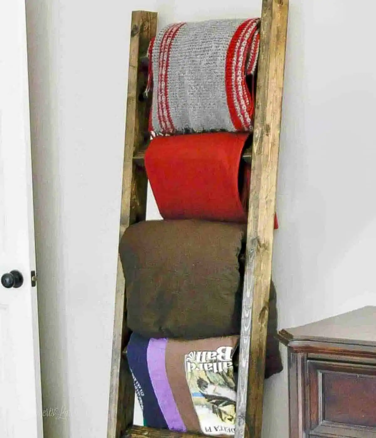 dark stained blanket ladder holding blankets, leaning against the wall.