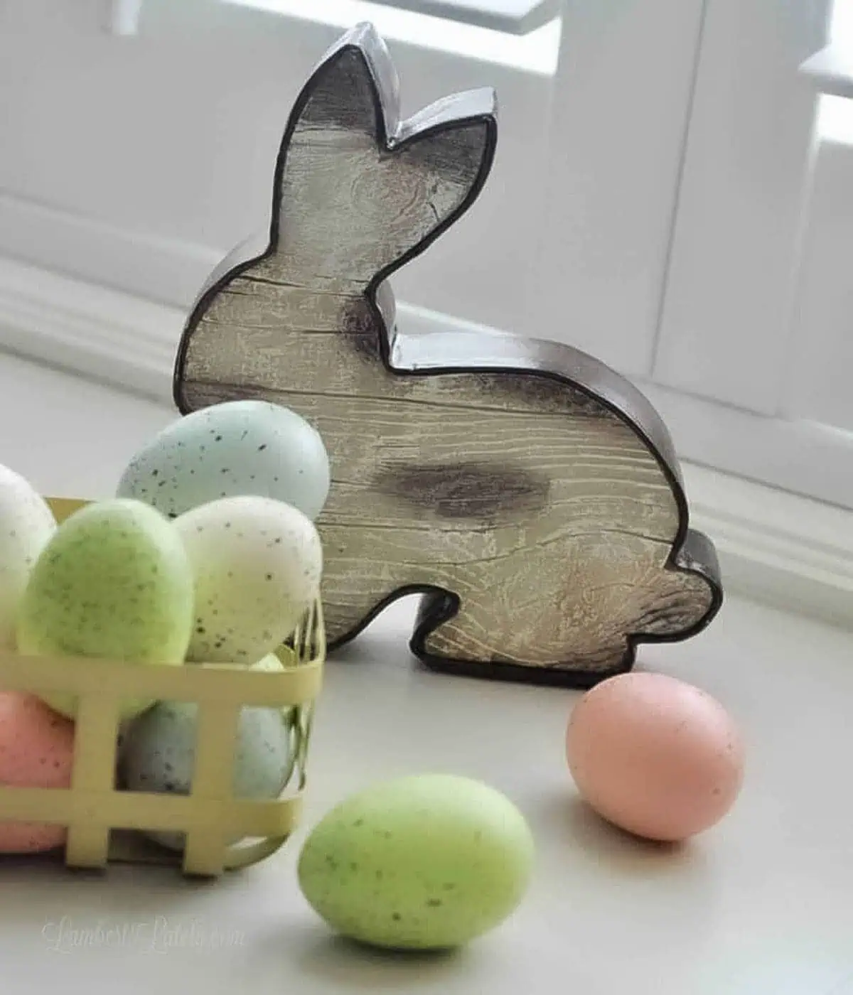 wooden easter bunny with pastel easter eggs in a yellow basket.