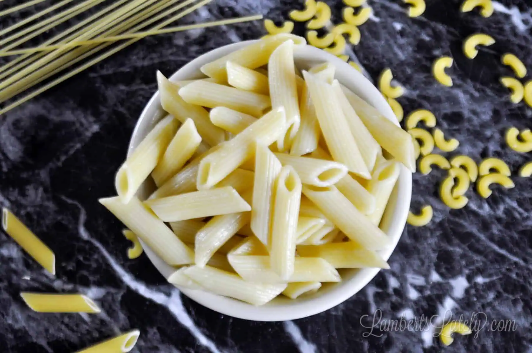 bowl of penne pasta on a black countertop.