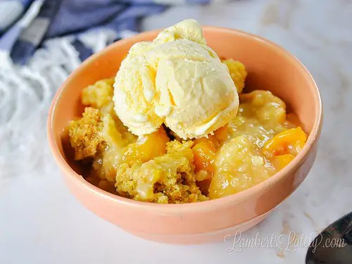 bowl of peach cobbler in front of a blue striped towel.