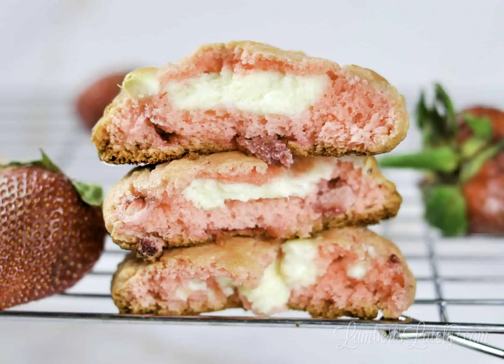 three strawberry cheesecake cookies on a baking rack.