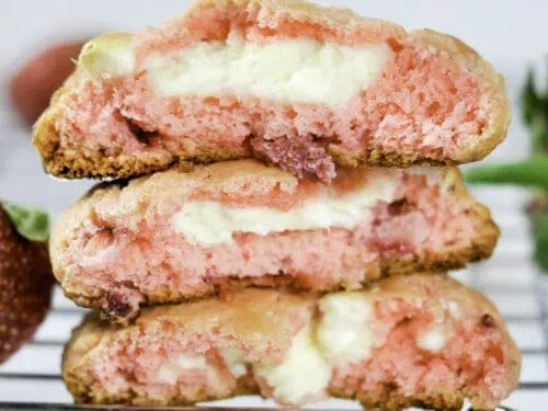 three strawberry cheeseake cookies cut in half on a baking rack.