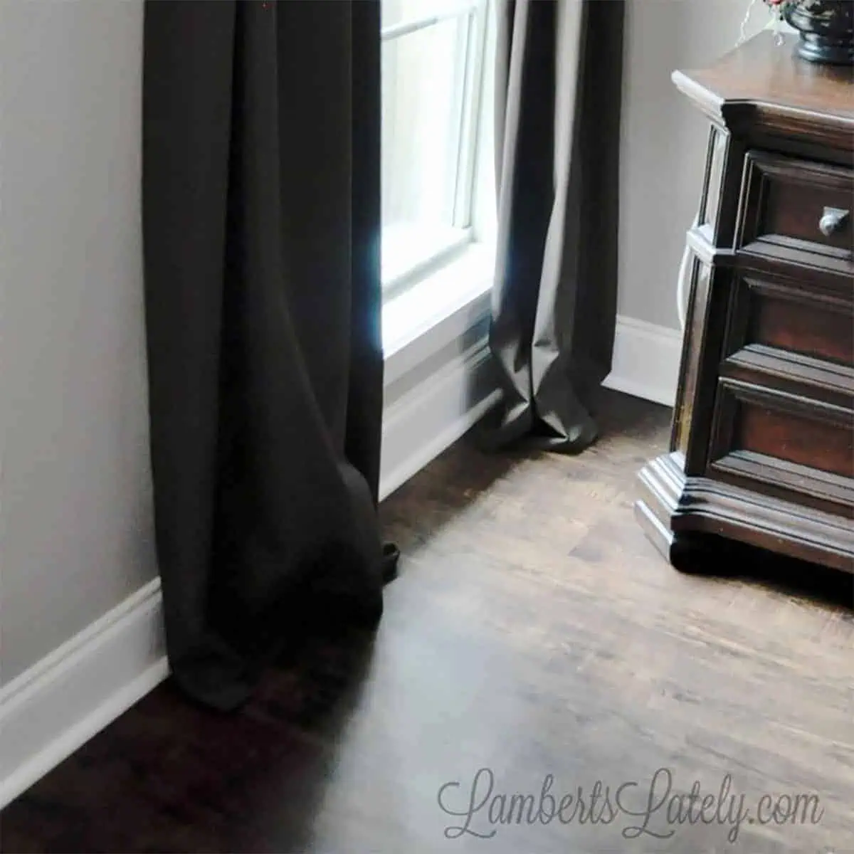 bottom of brown hemmed curtain panels hung on a window next to table.